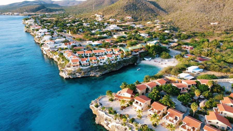 Cala turquesa y villas sobre el acantilado en Curaçao, los mercados inmobiliarios de Aruba y Curaçao con baja exposición climática