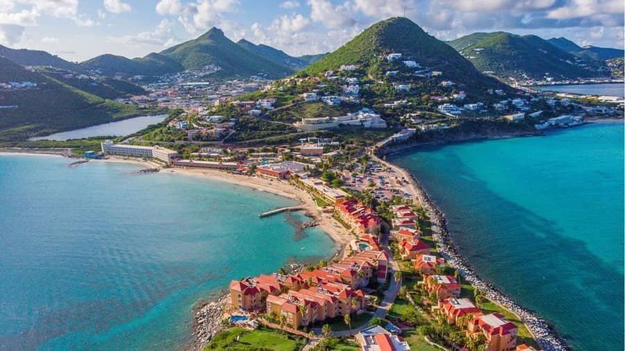 Vista aérea de Sint Maarten, residencias de tejados rojos entre dos bahías turquesas, inmobiliario del Caribe neerlandés
